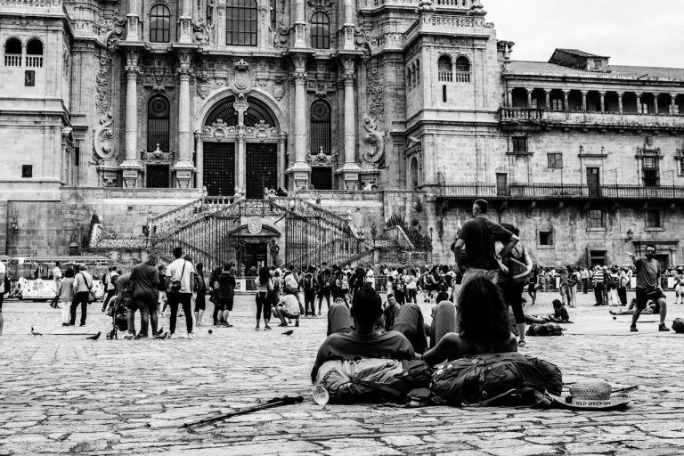 Monochrome scene of pilgrims resting near Santiago de Compostela Cathedral in Spain.